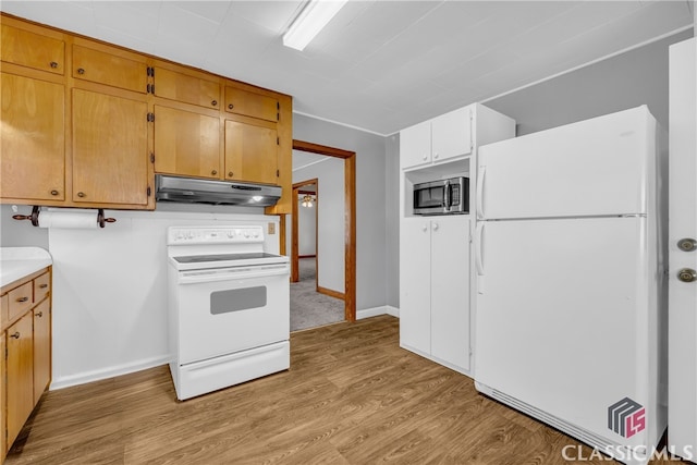 kitchen featuring light wood finished floors, under cabinet range hood, white appliances, light countertops, and baseboards