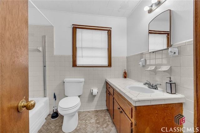 bathroom featuring vanity, a wainscoted wall, tile walls, toilet, and tile patterned floors