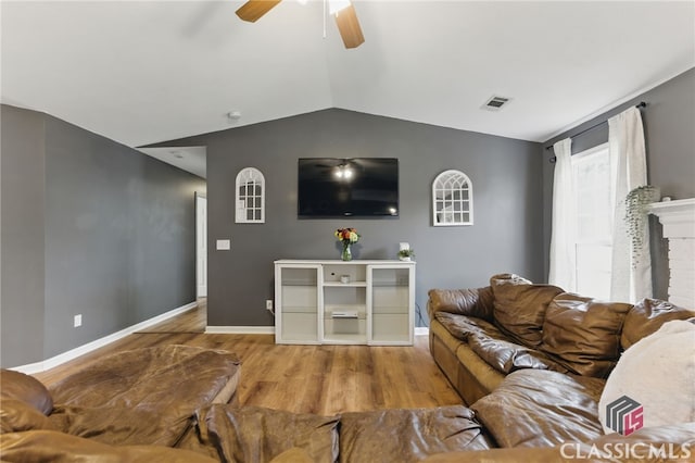 living area with vaulted ceiling, wood finished floors, visible vents, and baseboards