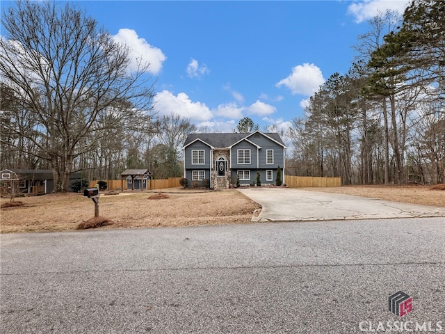 split foyer home with concrete driveway and fence