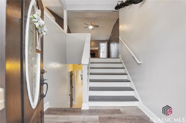 stairway with baseboards, ceiling fan, and wood finished floors