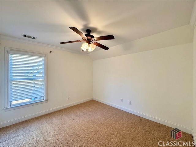 spare room with a ceiling fan, baseboards, visible vents, light carpet, and crown molding