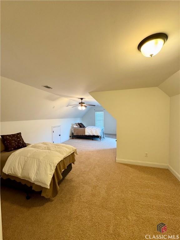 carpeted bedroom featuring visible vents, a ceiling fan, baseboards, and vaulted ceiling