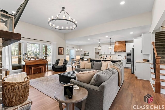 living area featuring recessed lighting, a notable chandelier, wood finished floors, and stairs