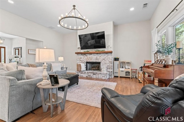 living area featuring a notable chandelier, recessed lighting, a fireplace, and wood finished floors