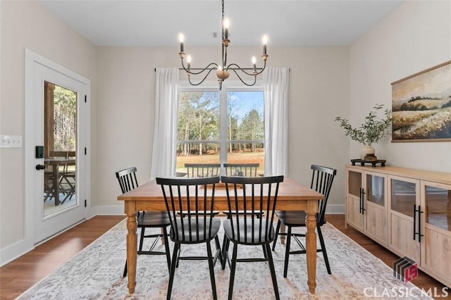 dining space with baseboards, plenty of natural light, a notable chandelier, and dark wood-style floors