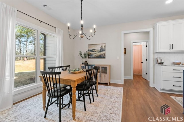 dining room featuring visible vents, baseboards, wood finished floors, and a chandelier