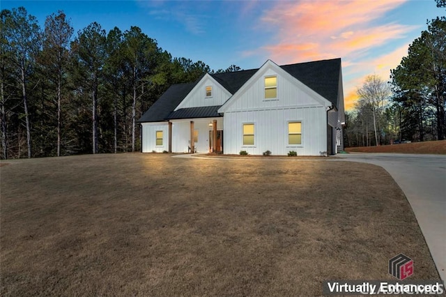 modern inspired farmhouse with board and batten siding, a front yard, metal roof, driveway, and a standing seam roof