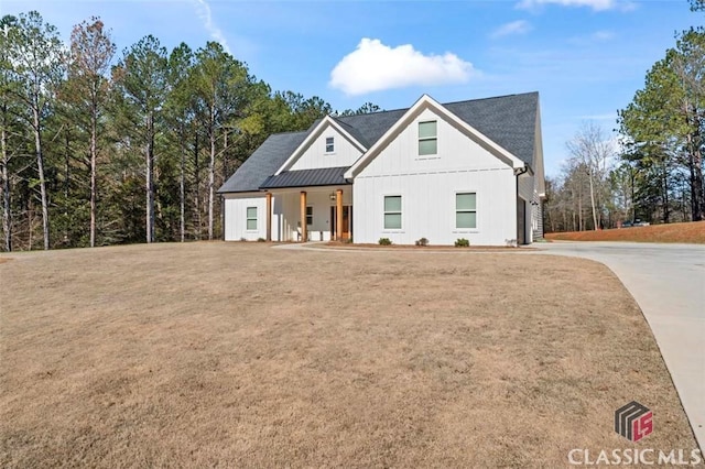 modern farmhouse style home featuring a front lawn, covered porch, board and batten siding, and metal roof