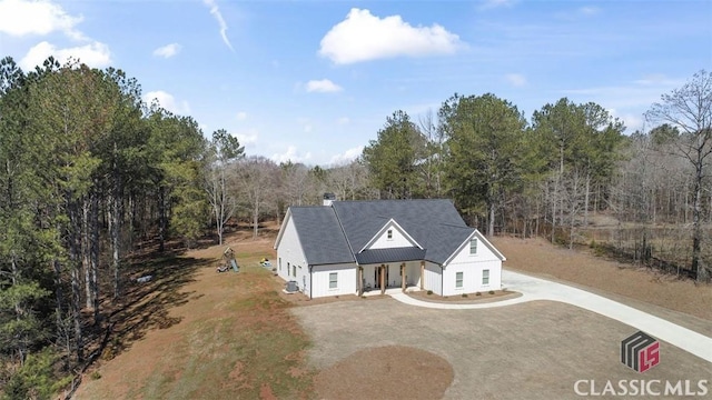 view of front of house with driveway and a view of trees