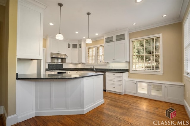 kitchen with a peninsula, a sink, white cabinets, glass insert cabinets, and under cabinet range hood