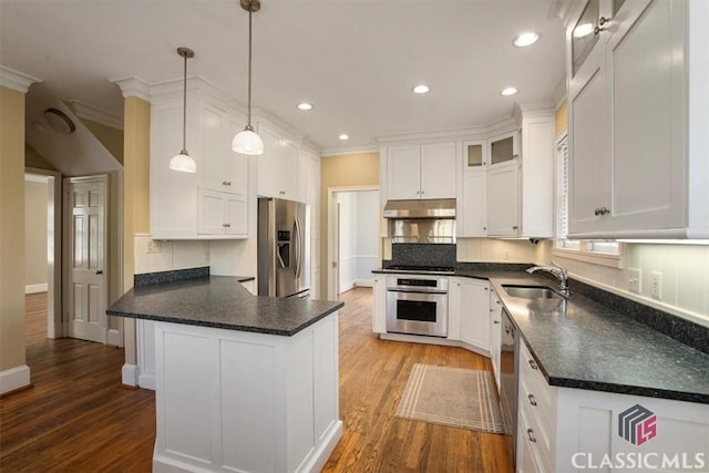 kitchen featuring a sink, under cabinet range hood, white cabinetry, stainless steel appliances, and a peninsula