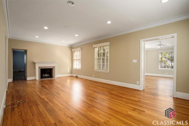 unfurnished living room with crown molding, a fireplace with flush hearth, recessed lighting, and light wood-type flooring