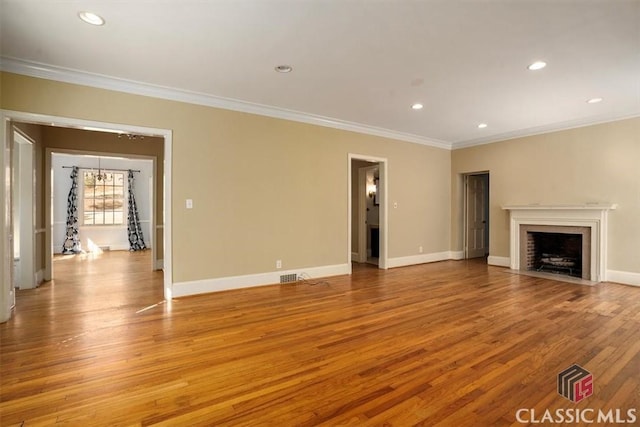 unfurnished living room with baseboards, light wood-style floors, ornamental molding, and a fireplace with flush hearth