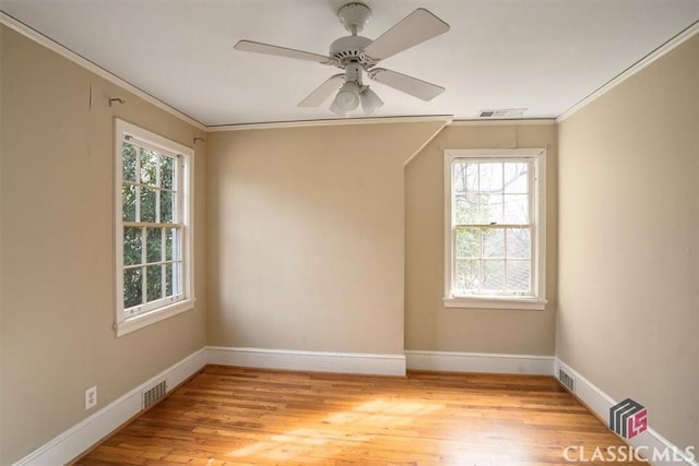 unfurnished room featuring light wood finished floors, visible vents, crown molding, and baseboards