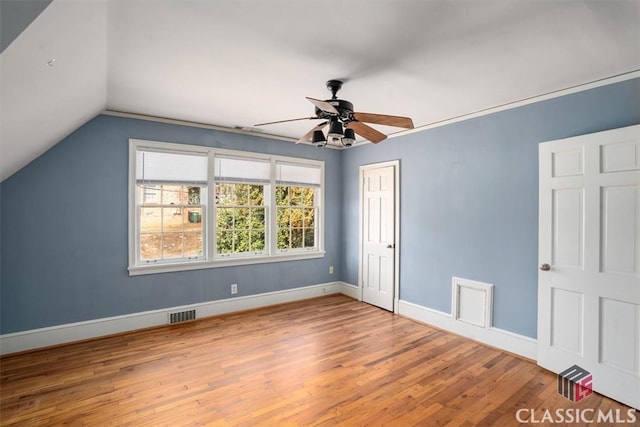 unfurnished bedroom with visible vents, a ceiling fan, wood finished floors, baseboards, and vaulted ceiling