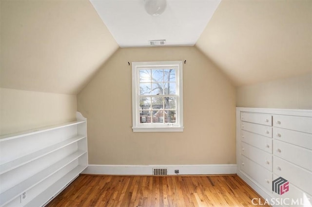 additional living space with visible vents, baseboards, lofted ceiling, and wood finished floors