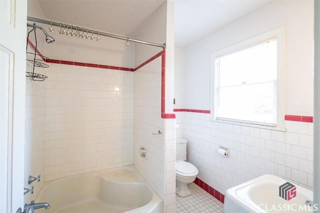 bathroom with tile patterned flooring, a wainscoted wall, toilet, shower / tub combination, and tile walls