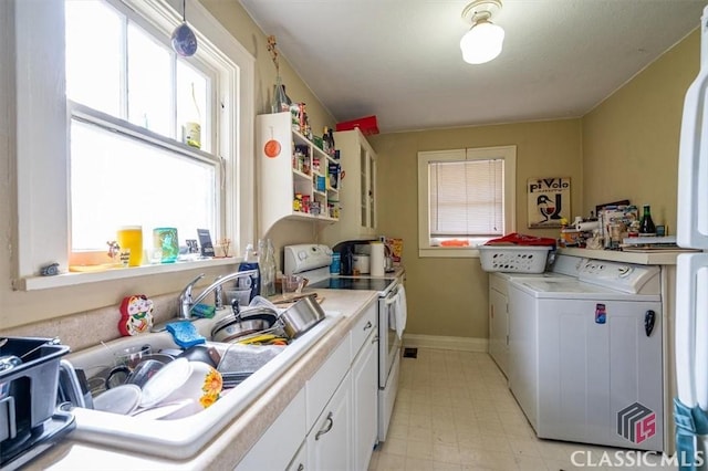 clothes washing area featuring a sink, separate washer and dryer, baseboards, light floors, and laundry area