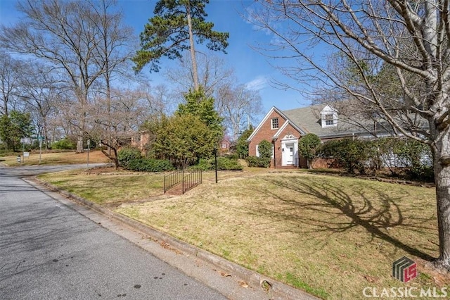 view of front facade featuring brick siding, a front yard, and fence