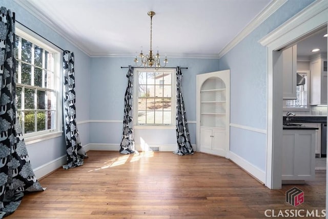 dining area with visible vents, baseboards, ornamental molding, an inviting chandelier, and wood finished floors