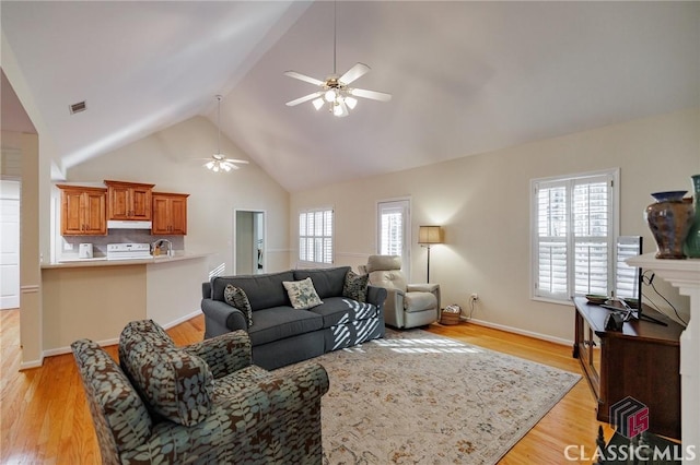 living room featuring a ceiling fan, visible vents, light wood finished floors, and high vaulted ceiling