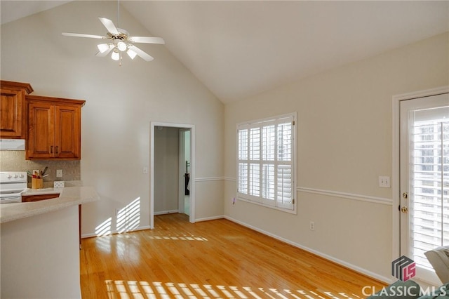 interior space with light wood finished floors, baseboards, high vaulted ceiling, and a ceiling fan