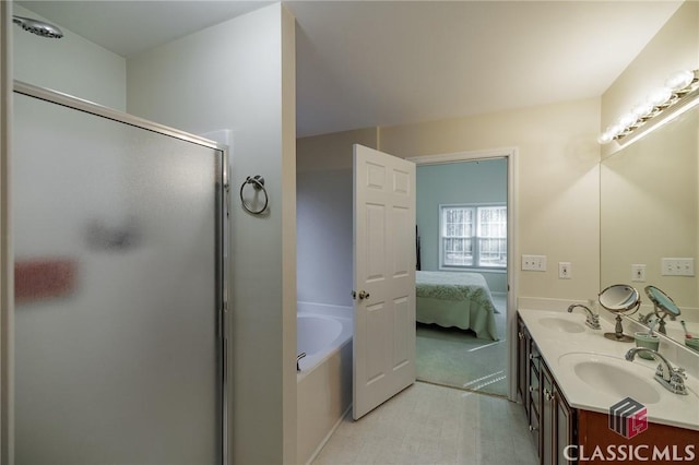 ensuite bathroom featuring connected bathroom, a bath, a stall shower, and a sink