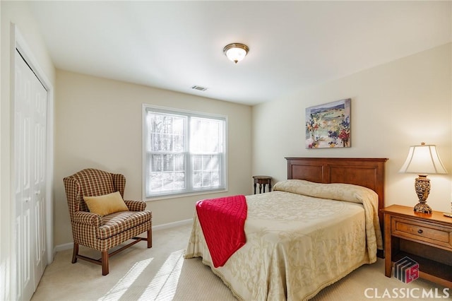 bedroom with baseboards, a closet, light carpet, and visible vents