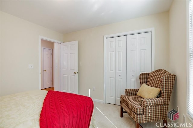 bedroom featuring a closet, baseboards, and light colored carpet