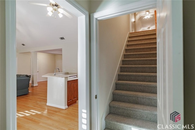 stairway featuring visible vents, baseboards, wood finished floors, and a ceiling fan