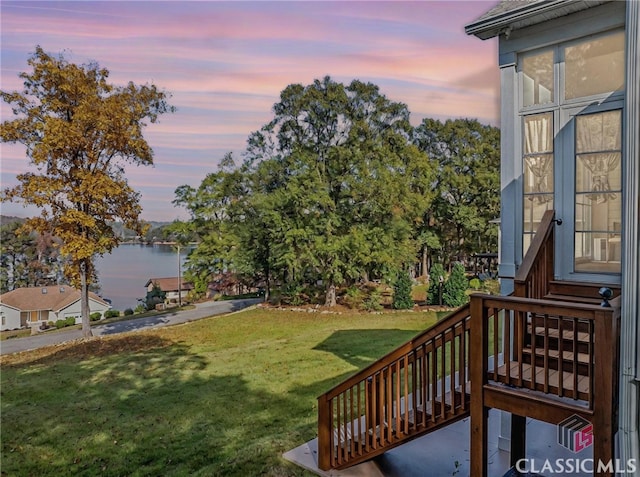 yard at dusk featuring a water view