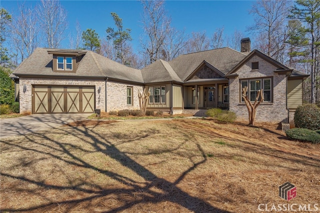 view of front of house with driveway, roof with shingles, a chimney, a garage, and brick siding