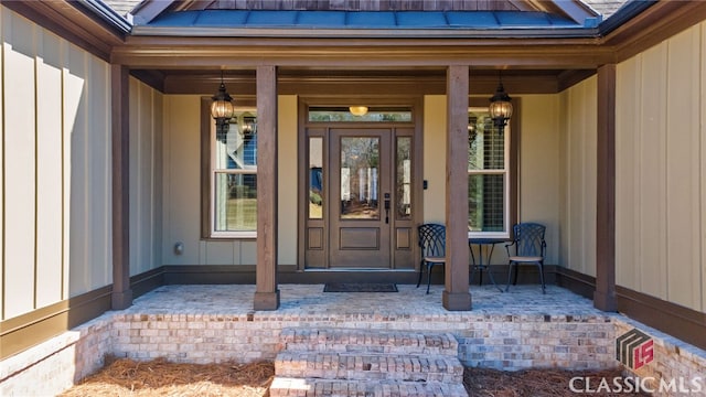 view of exterior entry with board and batten siding and covered porch