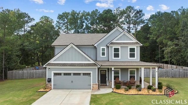 craftsman house with a front yard, concrete driveway, fence, and covered porch