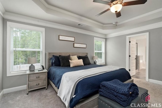 bedroom featuring a tray ceiling, light colored carpet, visible vents, and baseboards