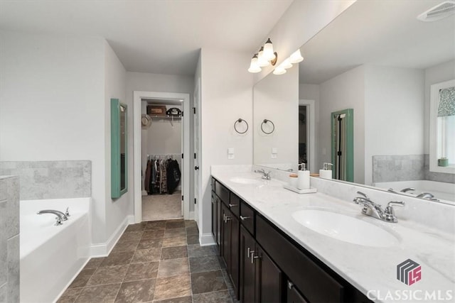 full bathroom with visible vents, double vanity, a sink, a spacious closet, and a garden tub