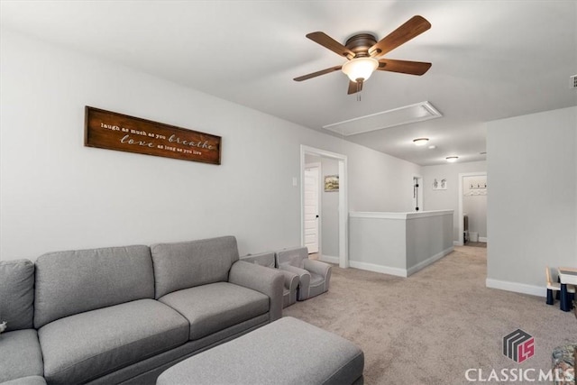 carpeted living area featuring baseboards, attic access, and ceiling fan