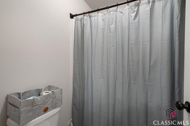 bathroom featuring a shower with shower curtain and toilet