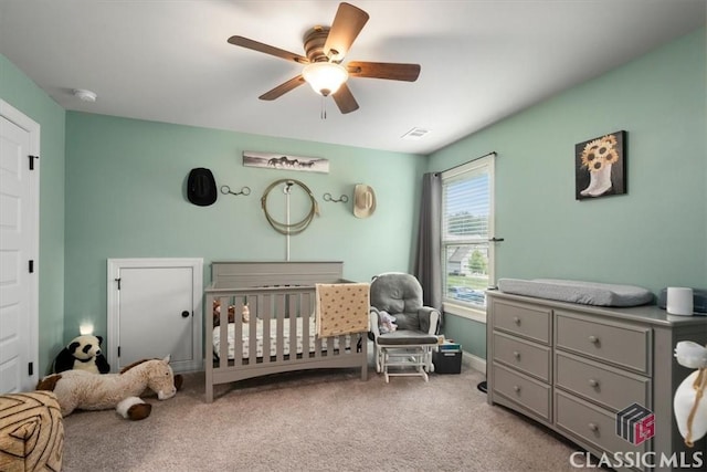 bedroom featuring visible vents, carpet floors, a crib, and a ceiling fan