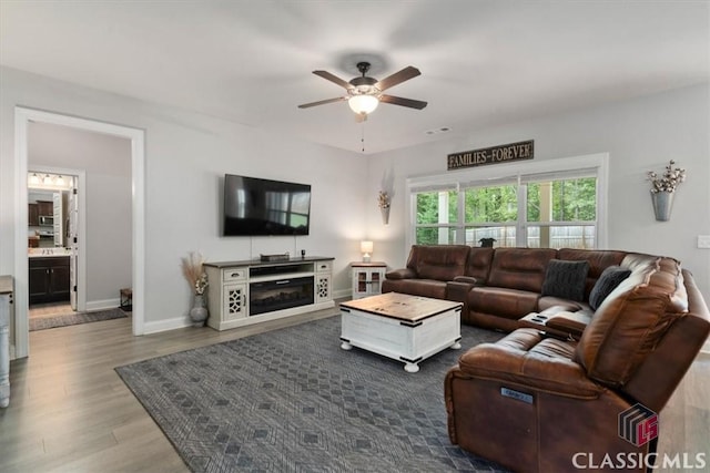 living room featuring visible vents, dark wood-style floors, baseboards, and ceiling fan
