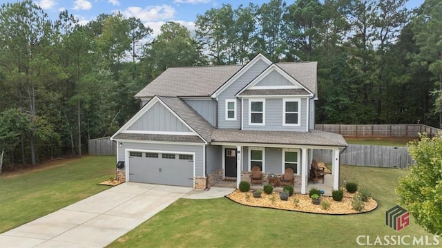 craftsman-style home with a shingled roof, fence, concrete driveway, a front yard, and covered porch