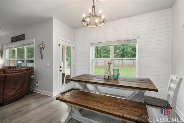 dining room featuring baseboards, wood finished floors, a healthy amount of sunlight, and a chandelier
