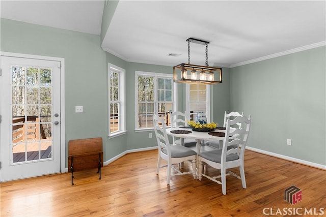 dining space featuring crown molding, wood finished floors, visible vents, and baseboards