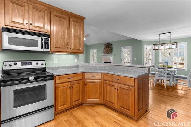 kitchen featuring a fireplace, a peninsula, brown cabinetry, and stainless steel appliances