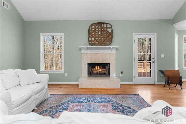 living area featuring visible vents, baseboards, wood finished floors, and a tile fireplace