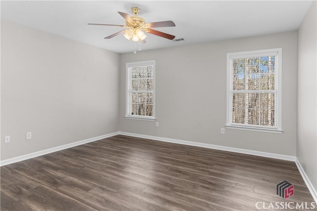 spare room featuring visible vents, baseboards, dark wood-style floors, and ceiling fan