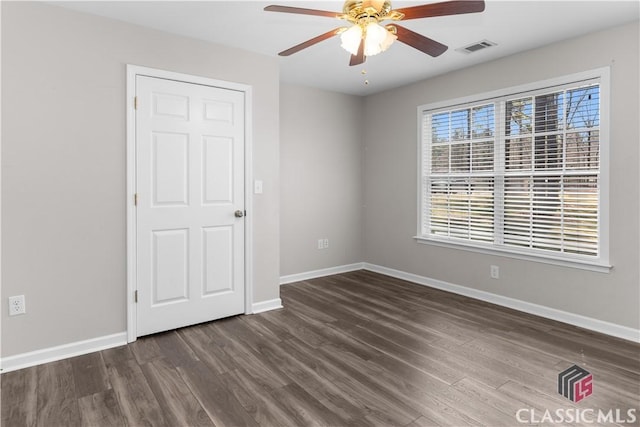 unfurnished room featuring dark wood finished floors, visible vents, baseboards, and ceiling fan