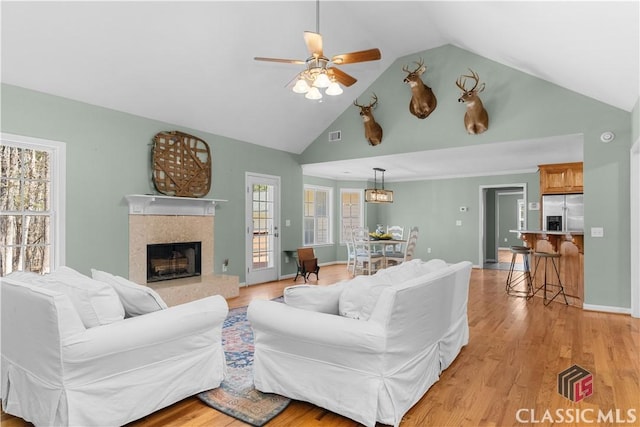 living room with baseboards, a ceiling fan, light wood-type flooring, and a premium fireplace