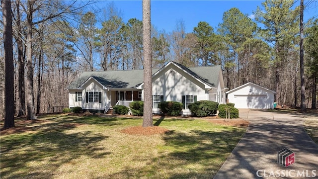 view of front facade with an outbuilding, driveway, a front lawn, a detached garage, and a porch